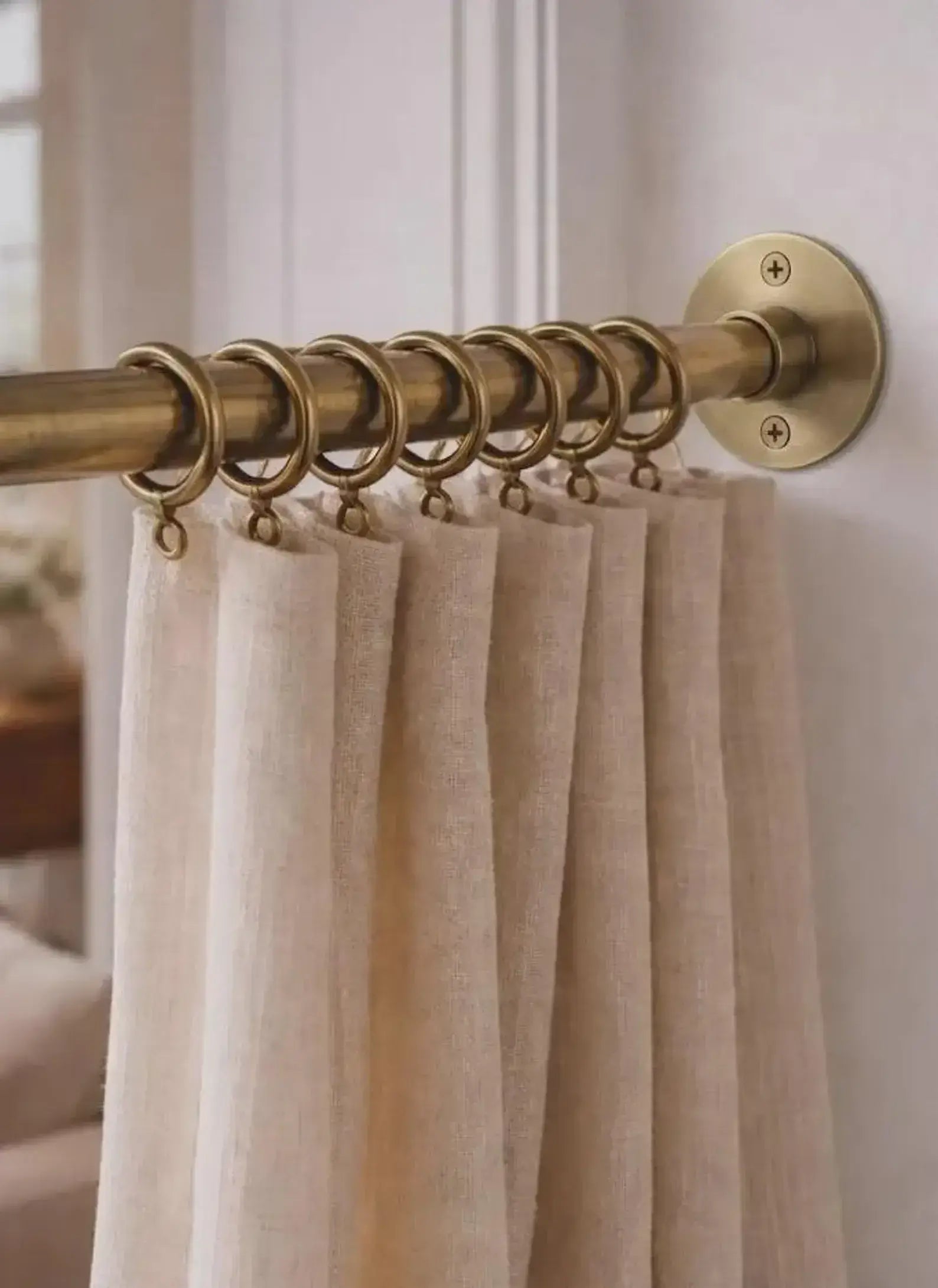brass shower curtain rod with beige curtains