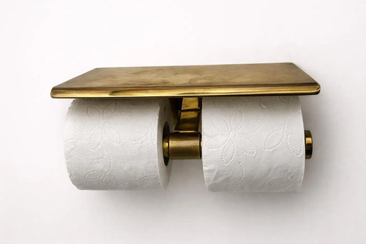 Wall mounted toilet paper holder with double brass shelf, showcasing elegance in a modern bathroom setting.