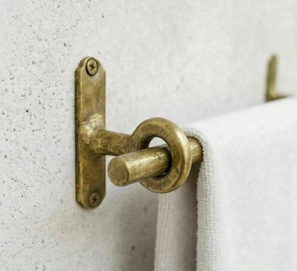 Unlacquered brass towel bar with ring supports, showcasing a modern design and durable finish.
