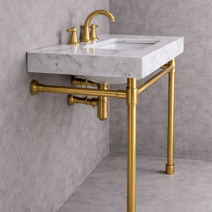 Marble sink with gold faucet and pipes against a gray wall.