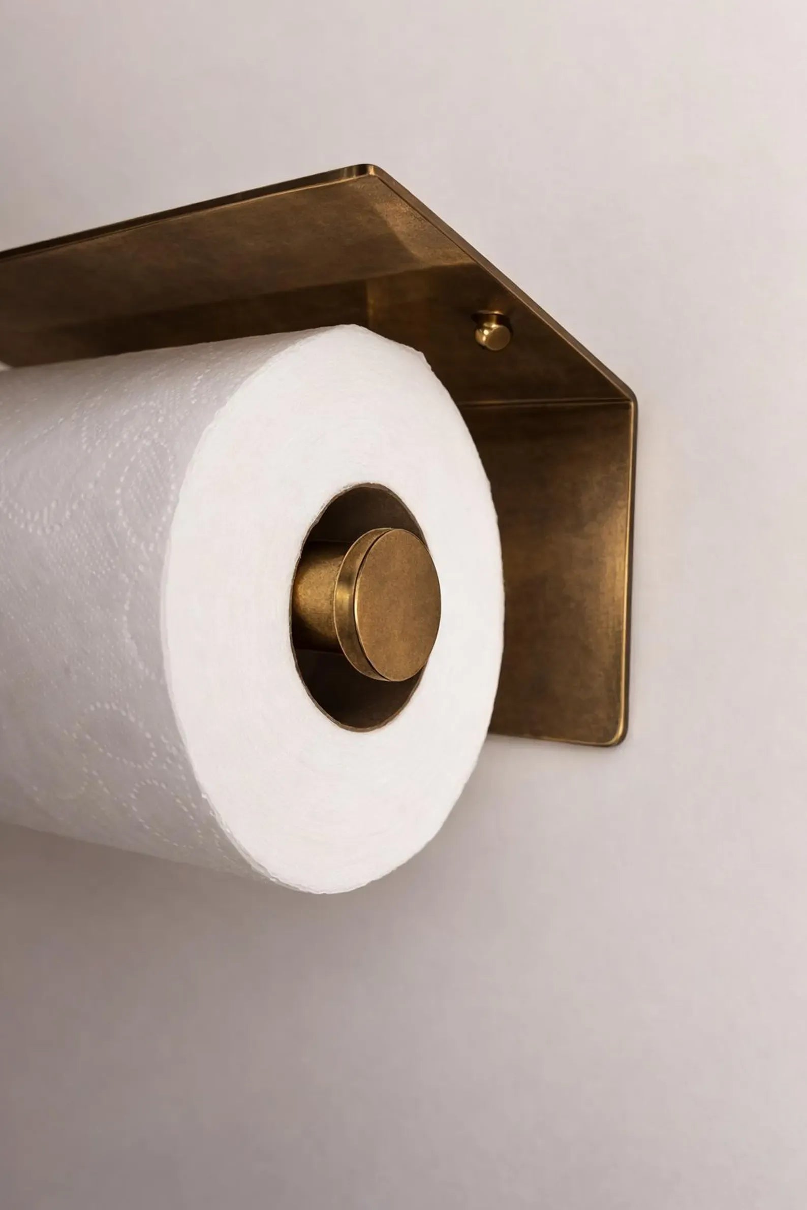 Wall mounted toilet paper holder with double brass shelf, showcasing elegance in a modern bathroom setting.